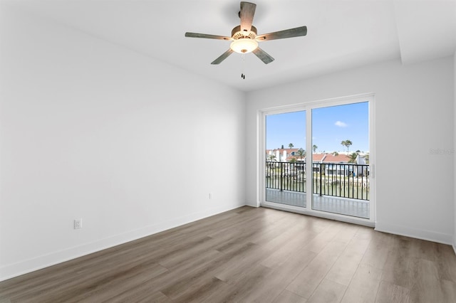 spare room with baseboards, wood finished floors, and a ceiling fan