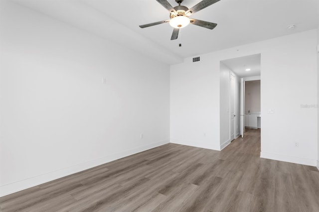 spare room with baseboards, ceiling fan, visible vents, and wood finished floors