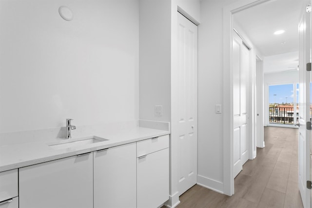 corridor featuring a sink and light wood-style floors