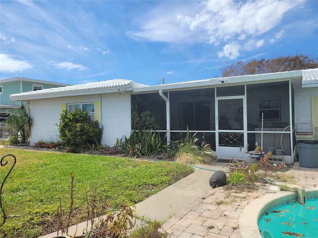 rear view of house featuring a lawn and a sunroom