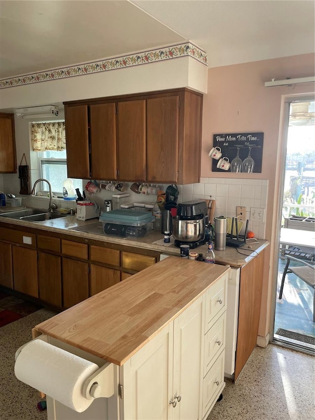 kitchen with butcher block counters, decorative backsplash, and sink