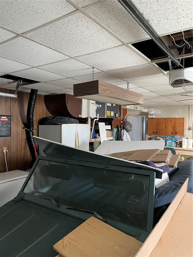 interior space featuring wood walls, white refrigerator, and a garage door opener