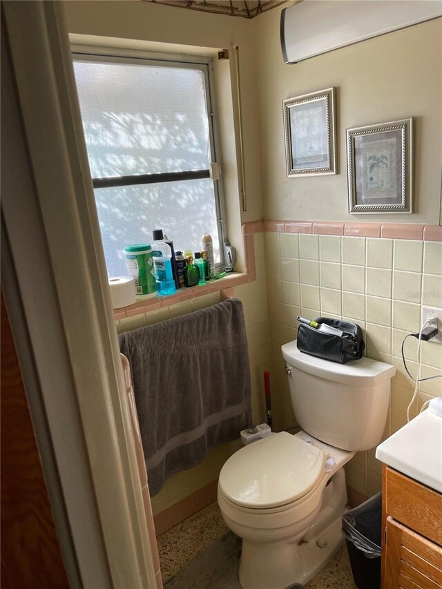 bathroom with vanity, toilet, and tile walls