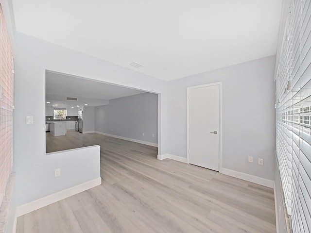 unfurnished living room with brick wall and light hardwood / wood-style floors