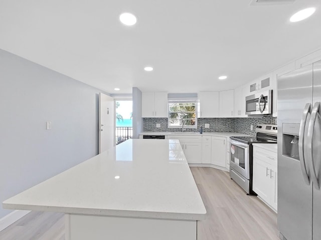 kitchen featuring a kitchen island, tasteful backsplash, stainless steel appliances, and white cabinets