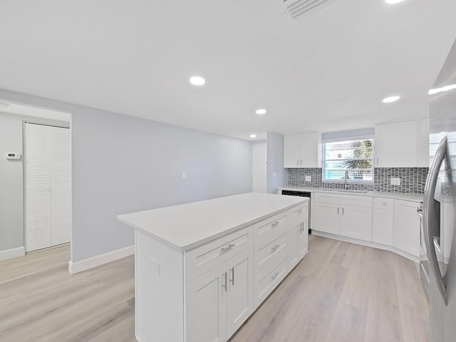 kitchen featuring light hardwood / wood-style floors, white cabinetry, backsplash, and a center island