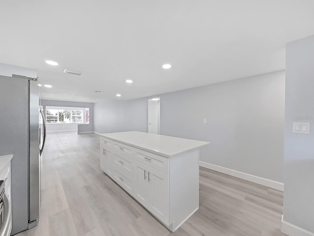 kitchen with a kitchen island, light hardwood / wood-style floors, stainless steel refrigerator, and white cabinetry