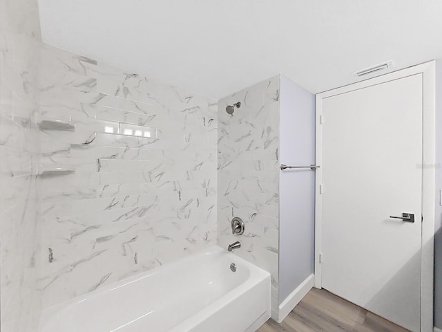 bathroom with tiled shower / bath combo and wood-type flooring