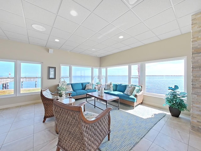 tiled living room with a drop ceiling and a water view