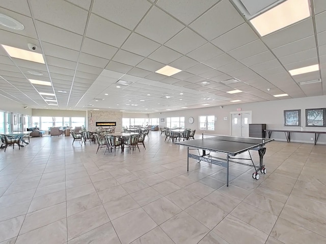 rec room featuring a drop ceiling, a large fireplace, and a healthy amount of sunlight