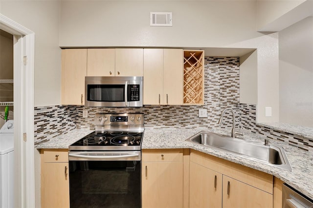 kitchen with sink, stainless steel appliances, backsplash, washer / dryer, and light brown cabinetry