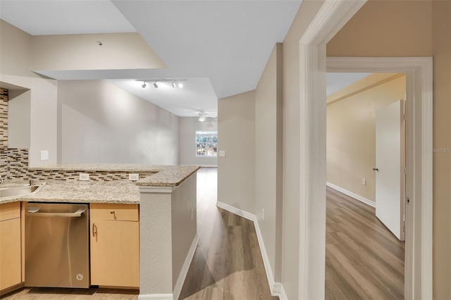 kitchen with light stone counters, stainless steel dishwasher, backsplash, light brown cabinetry, and light wood-type flooring