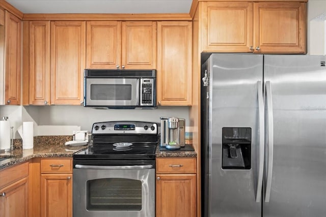 kitchen with stainless steel appliances and dark stone counters