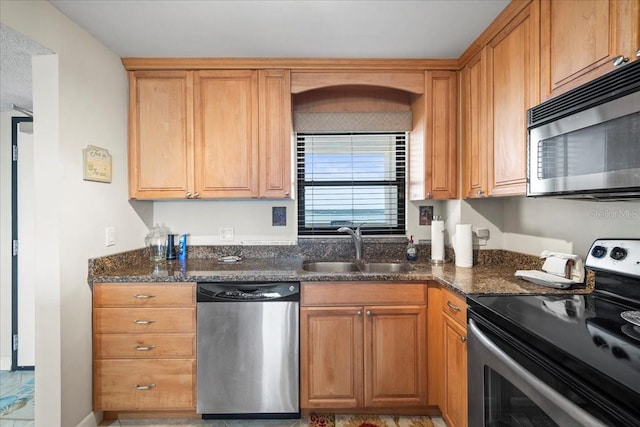 kitchen with tile flooring, stainless steel appliances, sink, and dark stone countertops