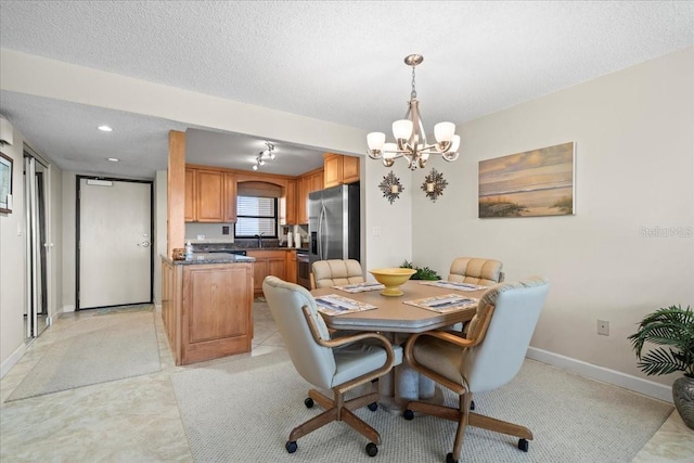 dining room featuring light tile floors, a notable chandelier, a textured ceiling, and sink