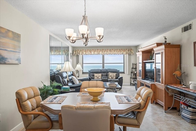 tiled dining room featuring a textured ceiling, a chandelier, and a water view