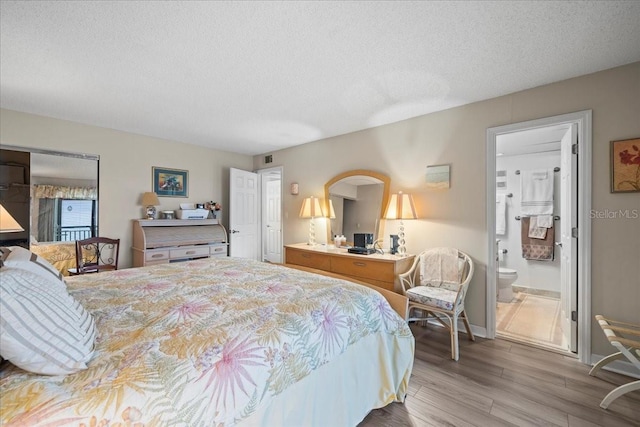 bedroom featuring a textured ceiling, connected bathroom, and wood-type flooring