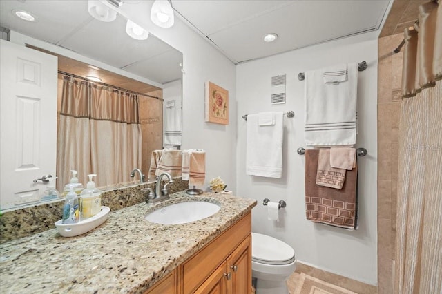 bathroom with tile flooring, large vanity, and toilet