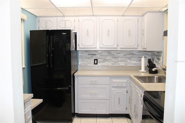 kitchen featuring light tile patterned flooring, tasteful backsplash, sink, white cabinets, and black appliances