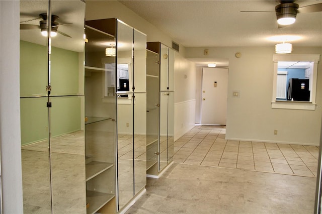 hall with light tile patterned flooring and a textured ceiling