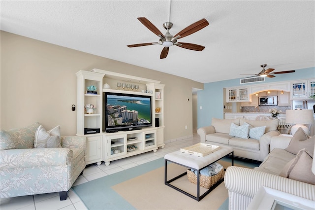 living room featuring ceiling fan, a textured ceiling, and light tile patterned flooring