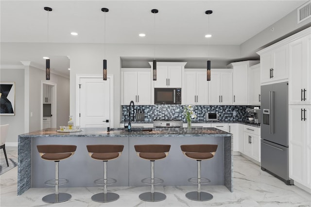 kitchen featuring tasteful backsplash, an island with sink, light tile floors, and high end refrigerator