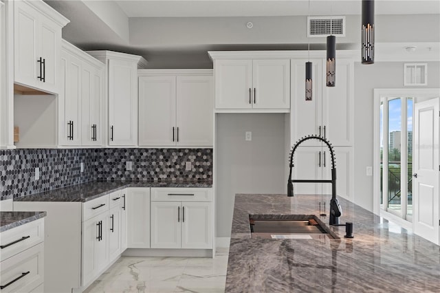 kitchen featuring white cabinets, sink, tasteful backsplash, light tile flooring, and dark stone counters