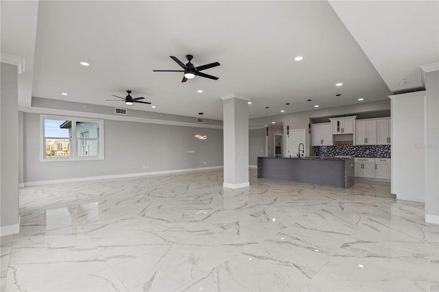 unfurnished living room featuring sink, ceiling fan, and light tile floors