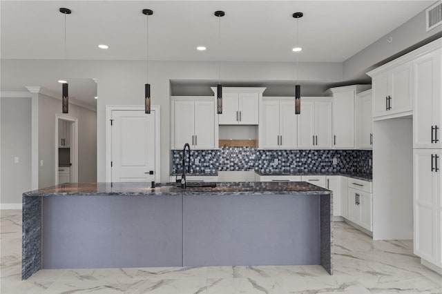 kitchen featuring tasteful backsplash, hanging light fixtures, and an island with sink