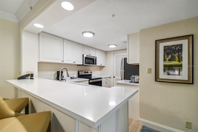 kitchen featuring kitchen peninsula, a kitchen breakfast bar, white cabinets, appliances with stainless steel finishes, and light hardwood / wood-style flooring