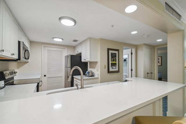 kitchen with white cabinets, stainless steel appliances, kitchen peninsula, and sink