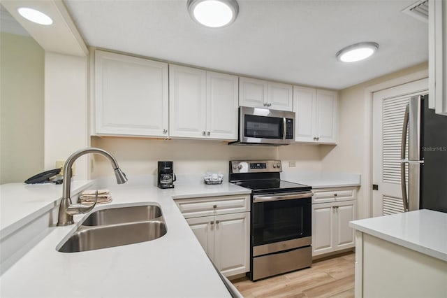 kitchen with light hardwood / wood-style floors, white cabinetry, stainless steel appliances, and sink