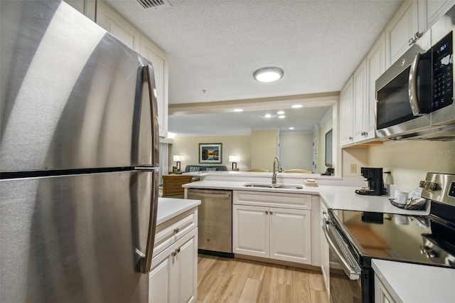 kitchen with kitchen peninsula, sink, appliances with stainless steel finishes, light hardwood / wood-style flooring, and white cabinetry