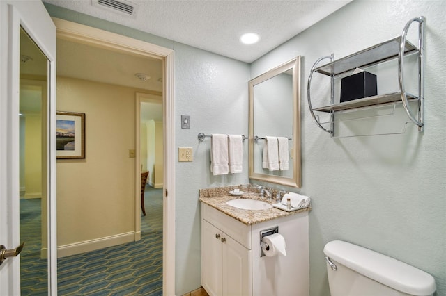 bathroom featuring a textured ceiling, tile floors, large vanity, and toilet