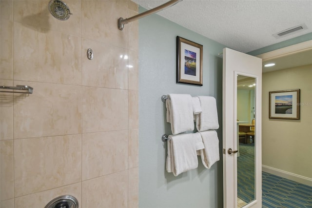 bathroom with a tile shower and a textured ceiling