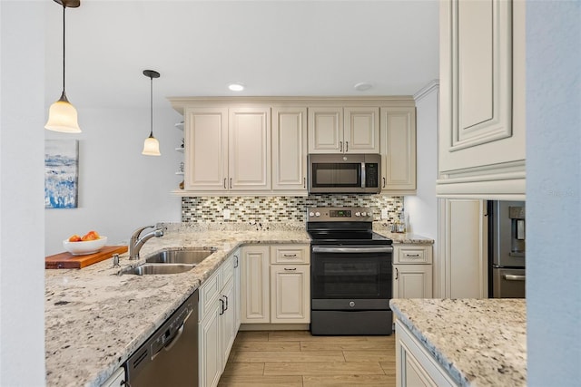 kitchen featuring pendant lighting, cream cabinetry, tasteful backsplash, appliances with stainless steel finishes, and sink