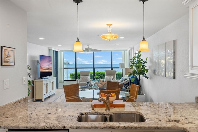 kitchen featuring hanging light fixtures, ceiling fan, sink, and a water view