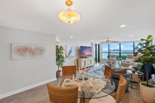 interior space with dark wood-type flooring, a wall of windows, ceiling fan, and a water view