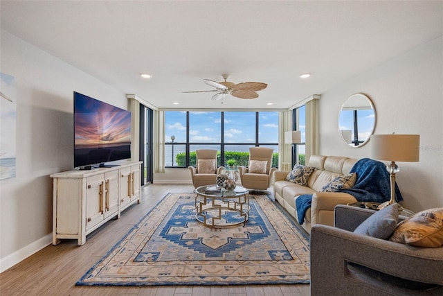 living room featuring floor to ceiling windows, light hardwood / wood-style floors, and ceiling fan