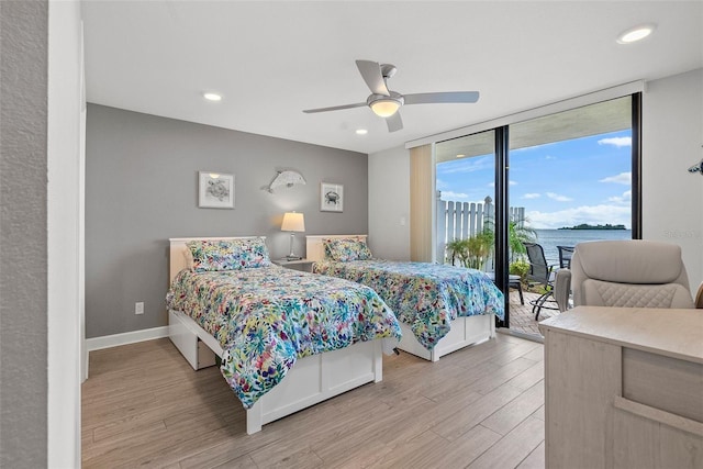 bedroom with ceiling fan, floor to ceiling windows, access to outside, light hardwood / wood-style floors, and a water view