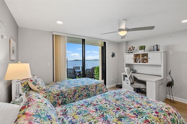 bedroom featuring ceiling fan, light wood-type flooring, a water view, access to outside, and floor to ceiling windows