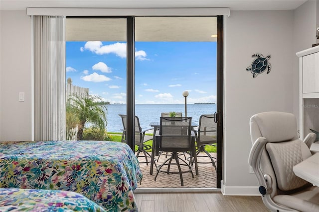 bedroom with a water view, access to exterior, and light hardwood / wood-style flooring