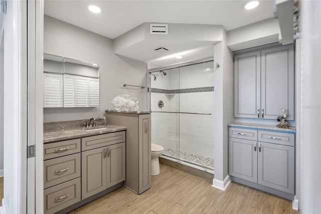 bathroom with oversized vanity, toilet, a shower with door, and hardwood / wood-style floors