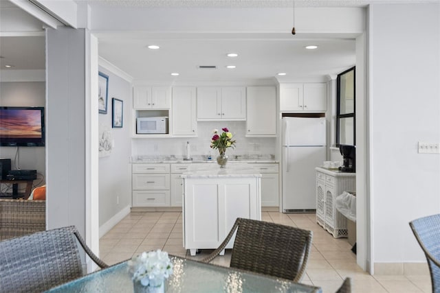 kitchen with light tile floors, tasteful backsplash, white appliances, and white cabinetry