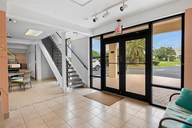 doorway with light tile floors, rail lighting, and french doors