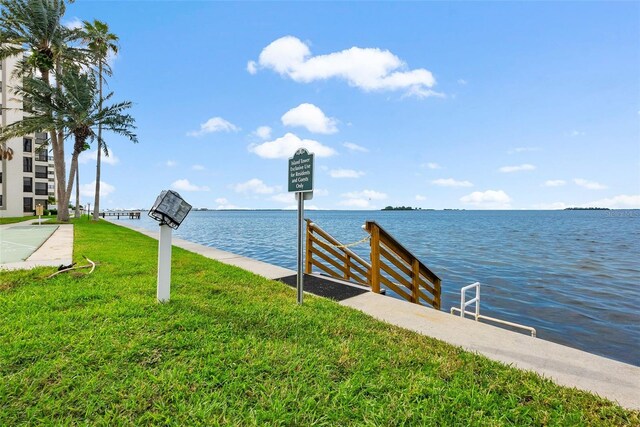 view of dock featuring a lawn and a water view