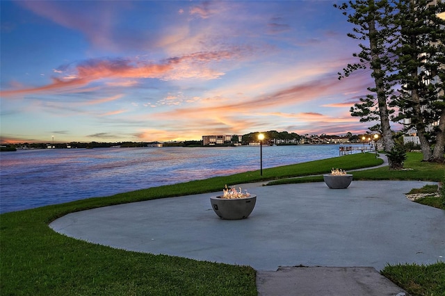 patio terrace at dusk with a water view and a lawn