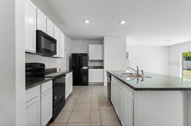 kitchen featuring an island with sink, light tile floors, black appliances, white cabinets, and sink