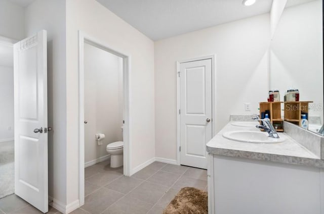 bathroom with toilet, tile floors, and dual bowl vanity