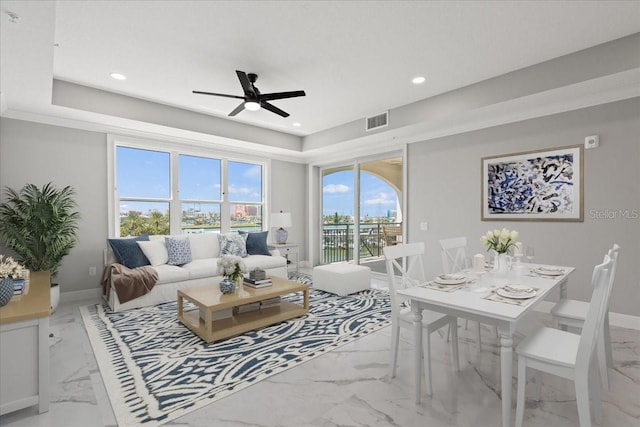 living room featuring ceiling fan, light tile floors, and a tray ceiling